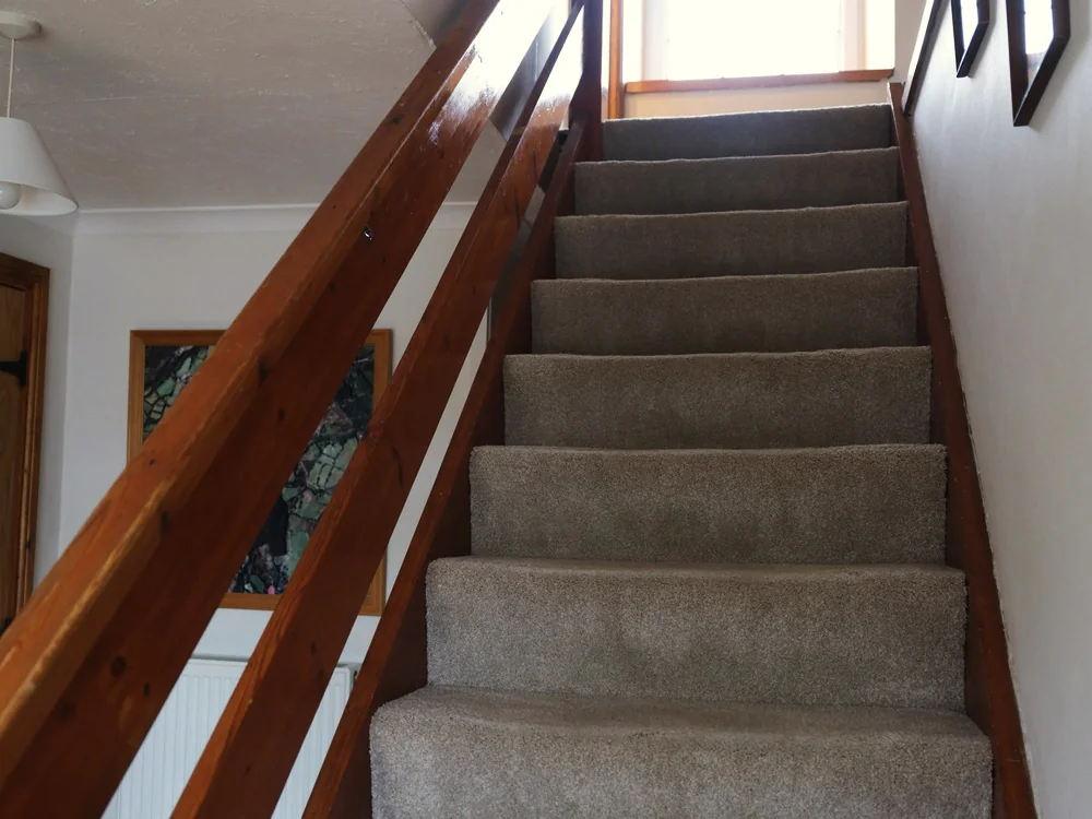 Gestoffeerde trap met een houten leuning langs de wand