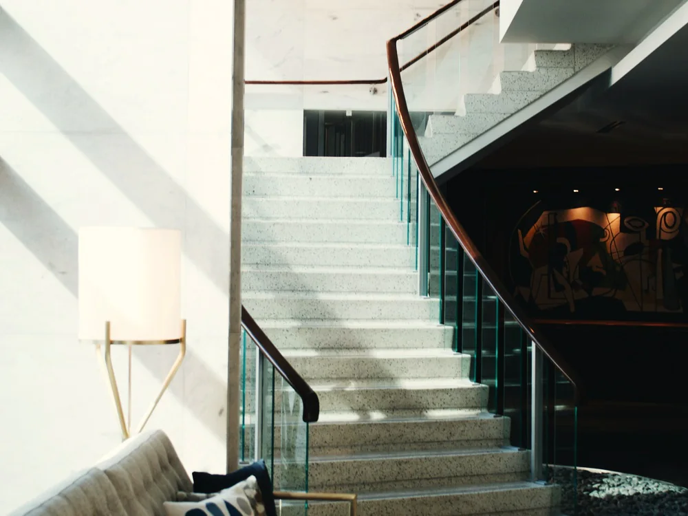 Trap met een glazen balustrade en een houten leuning