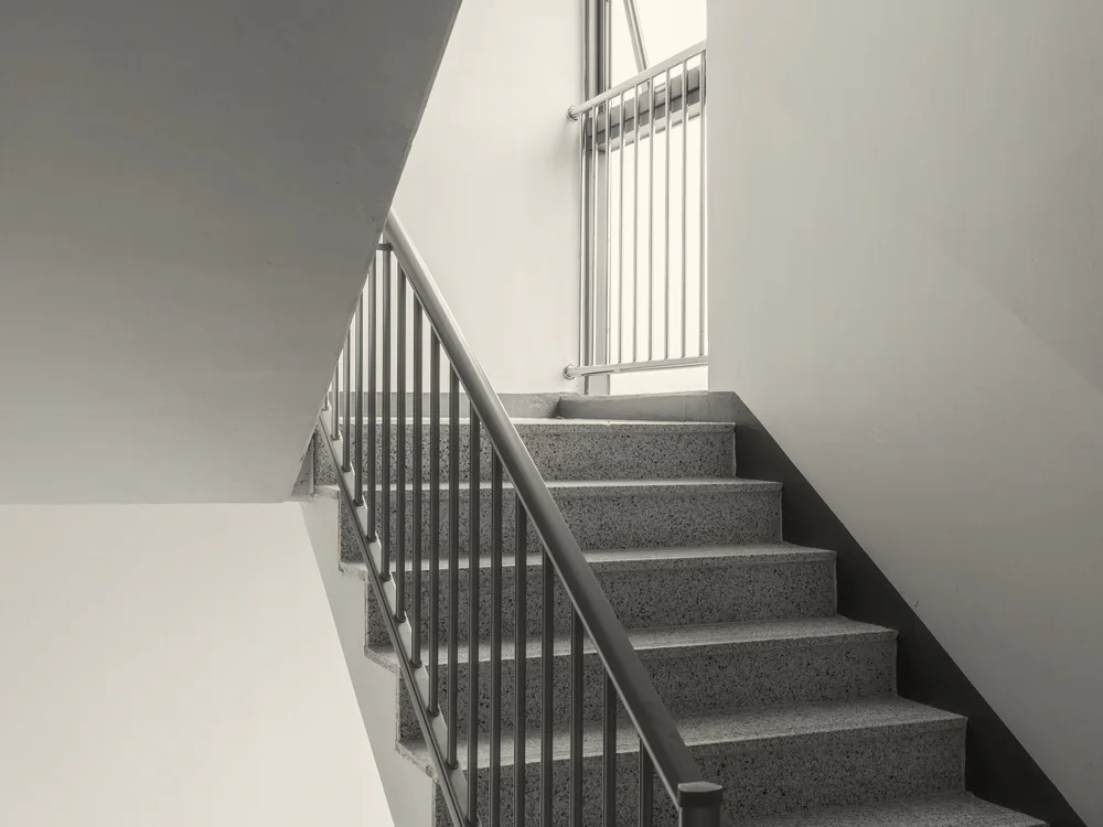 Grijze trap met een zwarte spijlenbalustrade