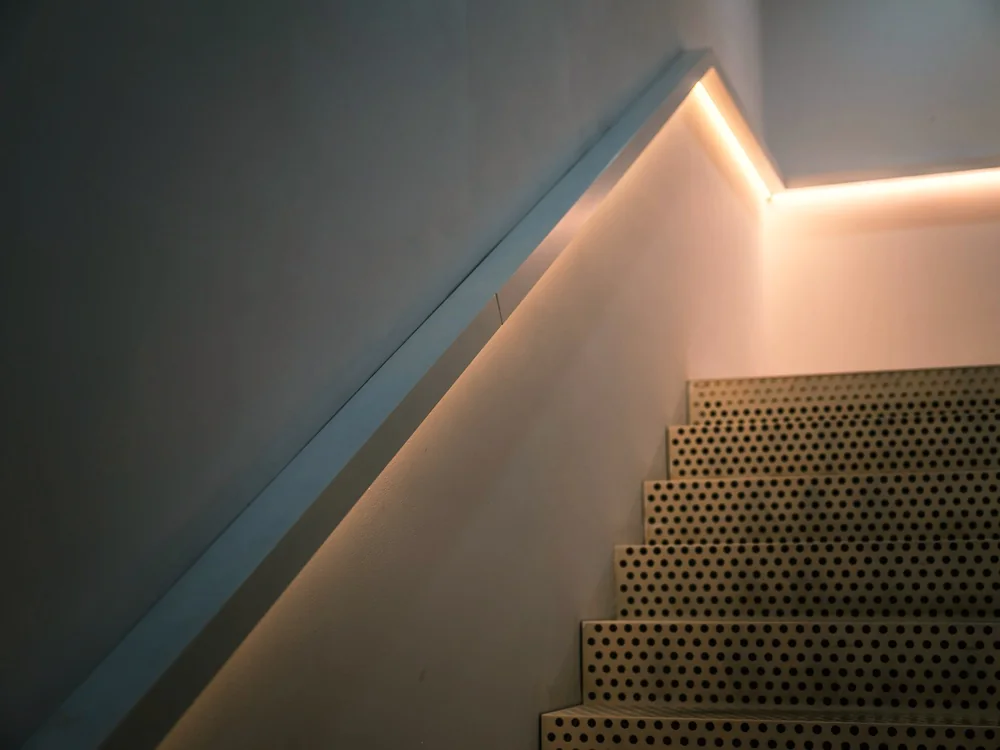 Trap met een verlichte leuning langs de wand