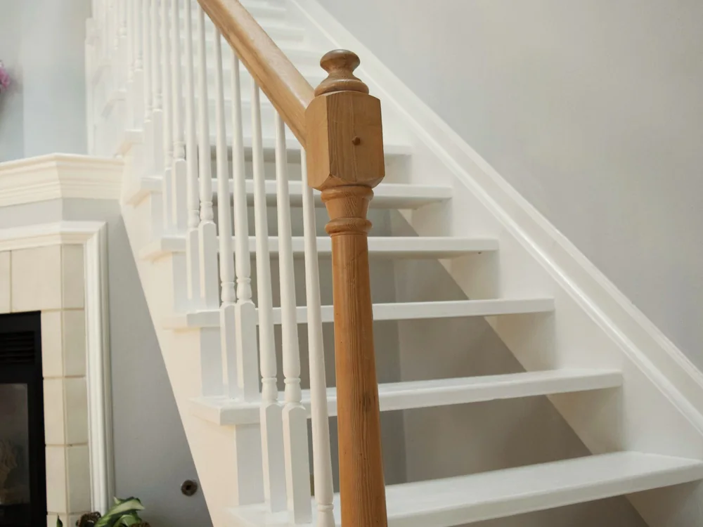 Witte trap met witte spijlen en een houten trappaal