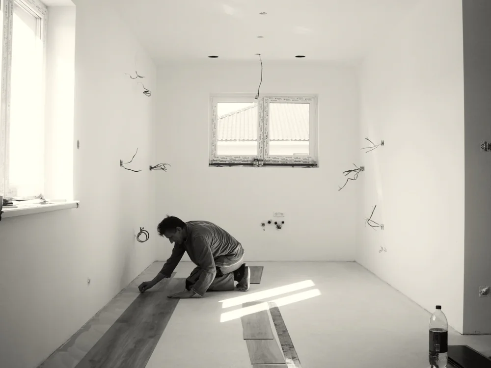 Vakman legt een nieuwe vloer in een lege kamer