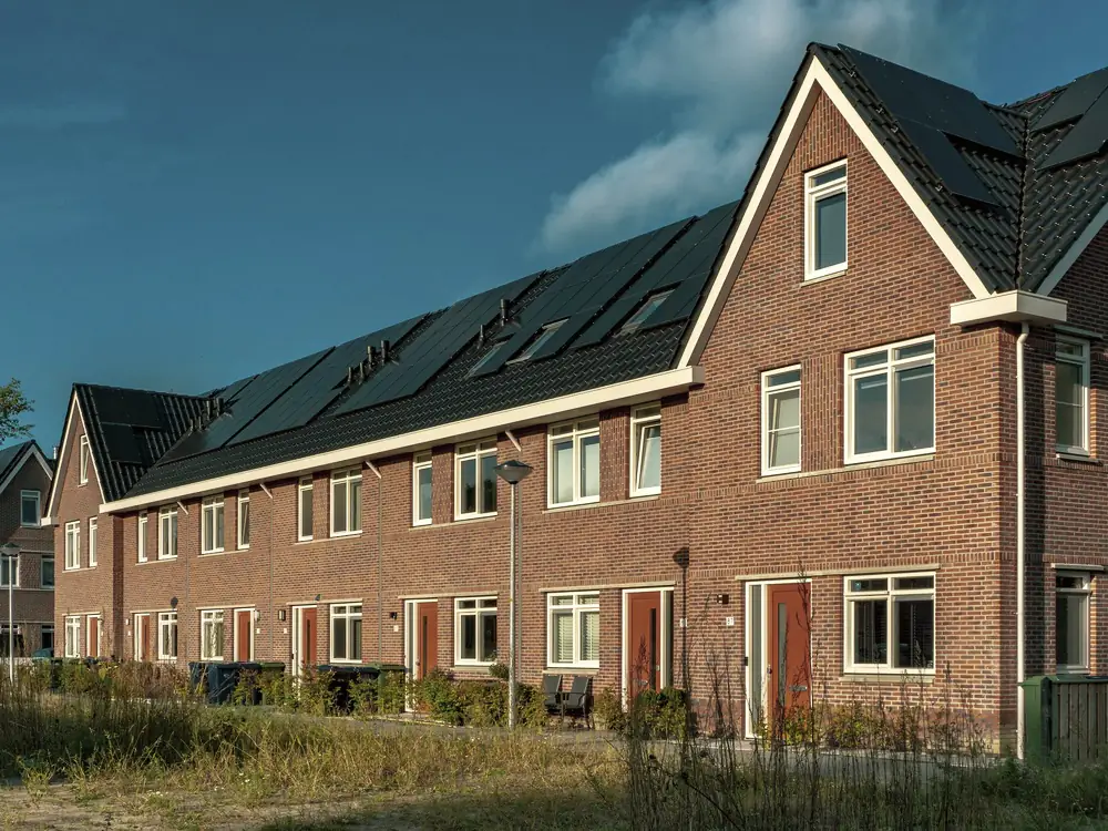 Rij nieuwbouwwoningen met zonnepanelen en een puntdak